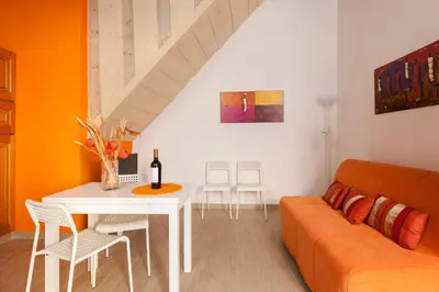 a living room with an orange couch and a table at Boccanera a Trastevere Holiday Apartment in Rome