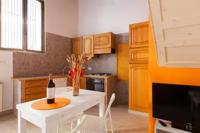 a kitchen with a white table with a bottle of wine at Boccanera a Trastevere Holiday Apartment in Rome