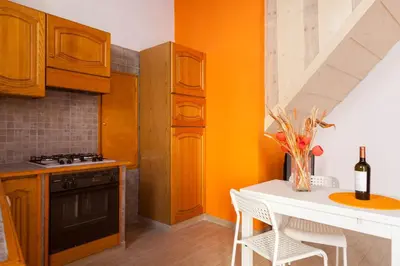 a kitchen with orange walls and a white table at Boccanera a Trastevere Holiday Apartment in Rome