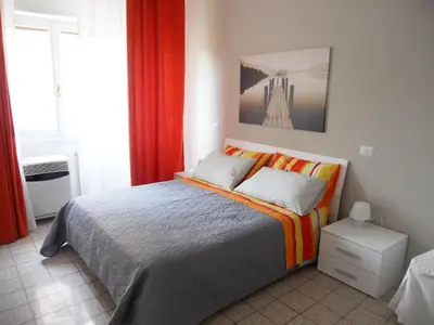 a bedroom with a large bed with orange curtains at Saint Peter's House in Rome