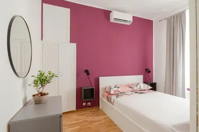 a bedroom with a white bed and a purple wall at La Casa Di Rinny - Vaticano in Rome