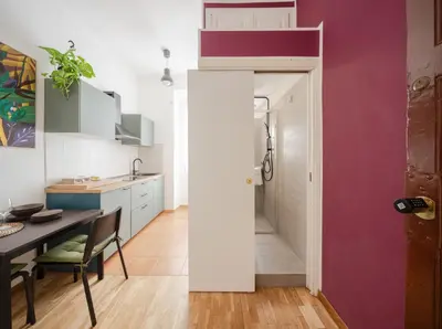 a kitchen and dining room with a dining table and a red wall at La Casa Di Rinny - Vaticano in Rome