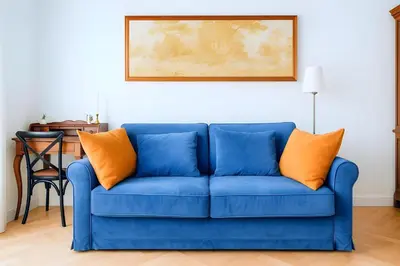 a blue couch with orange pillows in a living room at Elegantis Milos Suite Apartment - Your Chic Retreat in Central Rome in Rome