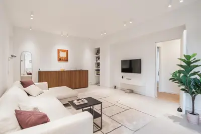 a white living room with a white couch and a tv at GuestHost - Pannonia Colosseum in Rome