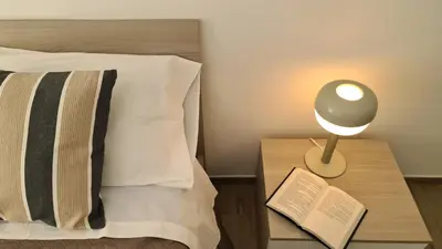 a bed with a lamp and a book on a night stand at LoveRhome Apartment 14 in Rome