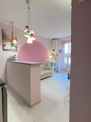 a kitchen and living room with a pink wall at Vacanze Romane a San Giovanni in Rome