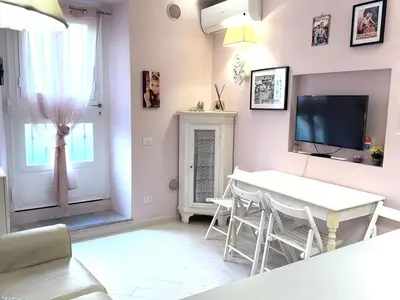 a living room with a table and a tv on the wall at Vacanze Romane a San Giovanni in Rome