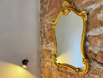 a gold mirror hanging on a brick wall at Nice 2 CU in Rome