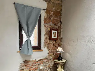 a window with a blue curtain on a brick wall at Nice 2 CU in Rome