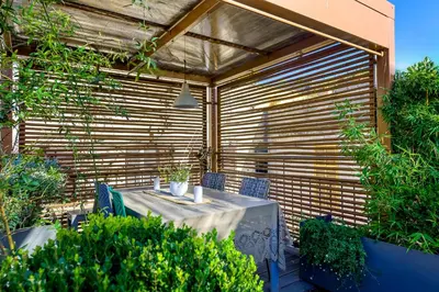 a table and chairs on a patio with a wooden wall at Skylife Eco-Luxe Trastevere Haven in Rome