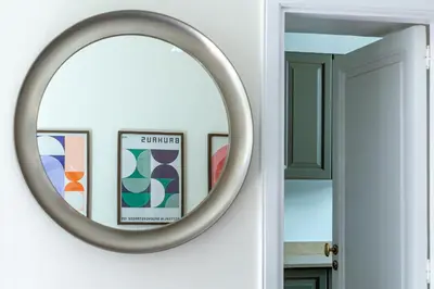 a round mirror on a wall with framed pictures at iFlat Monti Life with Elegance, Comfort and Beauty in Rome