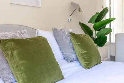 a bed with green and grey pillows on it at iFlat Monti Life with Elegance, Comfort and Beauty in Rome