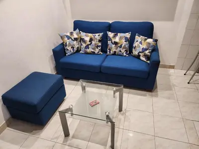 a blue couch with pillows and a glass table at La casetta di Marco in Rome