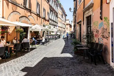 a street with people sitting at tables in an alley at Loft Trastevere 2 floors in Rome