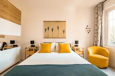 a bedroom with a bed and a yellow chair at Borgo Felix - Authentic Roman Living in Quadraro in Rome