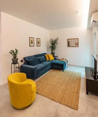 a living room with a blue couch and a yellow chair at Borgo Felix - Authentic Roman Living in Quadraro in Rome