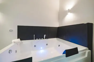 a white bath tub in a bathroom with black tiles at Monteverde Vatican in Rome