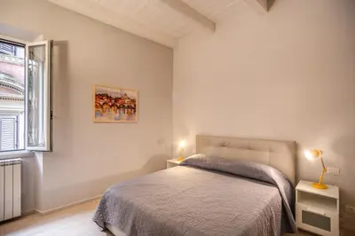 a white bedroom with a bed and a window at Agnello Apartment in Rome