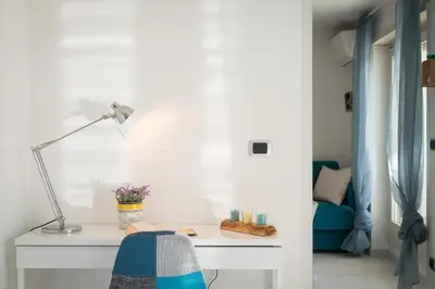 a white desk with a lamp and a blue couch at Boutique Domus Trastevere Penthouse in Rome