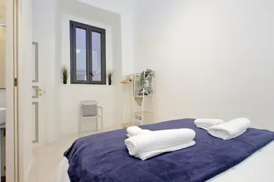 a white room with a bed with white pillows on it at Principe Amedeo piano terra in Rome
