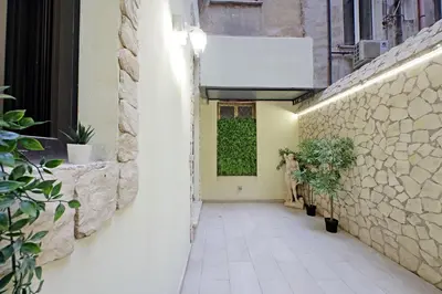 an alley with a wall with a window and plants at Principe Amedeo piano terra in Rome