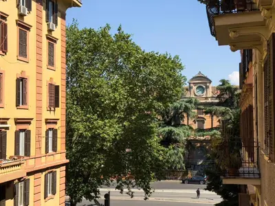 a tree in front of a building with a clock tower at Quiet retreat in Trastevere - ZENO 45 in Rome