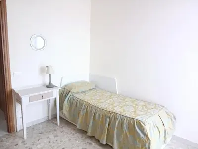 a white bedroom with a bed and a nightstand with a lamp at WelcHomeRome in Rome