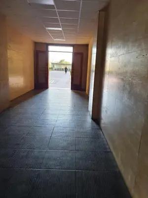 an empty hallway of a building with a person walking in the distance at House in the shopping street at Trastevere station in Rome
