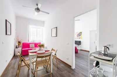 a dining room and living room with a table and chairs at House in the shopping street at Trastevere station in Rome