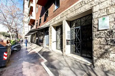 a person walking down a sidewalk next to a building at House in the shopping street at Trastevere station in Rome