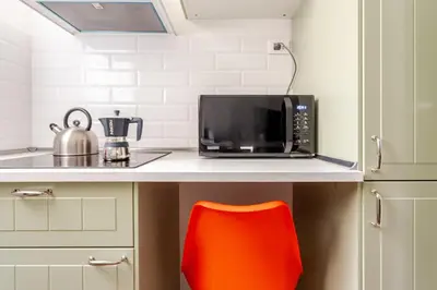 a kitchen counter with a microwave and a red chair at Funky 3BR Flat, Scenic Tram to Colosseum 7 Stops in Rome