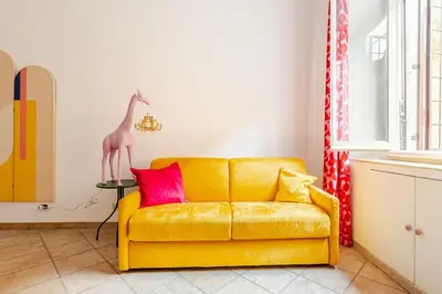 a yellow couch in a room with a giraffe on a table at Funky 3BR Flat, Scenic Tram to Colosseum 7 Stops in Rome