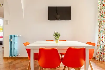a white table with orange chairs and a tv on a wall at Funky 3BR Flat, Scenic Tram to Colosseum 7 Stops in Rome