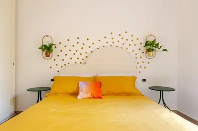 a bedroom with a bed with yellow sheets and two tables at Funky 3BR Flat, Scenic Tram to Colosseum 7 Stops in Rome