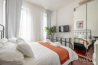 a bedroom with a large white bed with an orange blanket at Comfy and Elegant Apartment in Rome