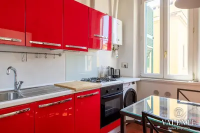 a kitchen with red cabinets and a sink and a table at Comfy and Elegant Apartment in Rome