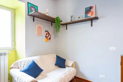 a living room with a white couch and blue pillows at Loft16 Rome - 10 min PlGNETO - COLOSSEO in Rome