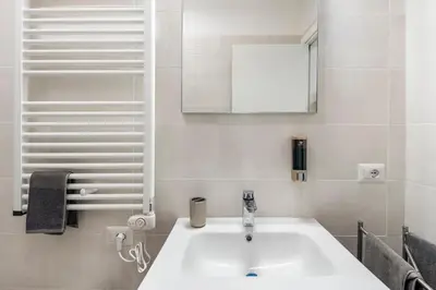 a bathroom with a white sink and a mirror at Brand new apartment with private parking space in Rome