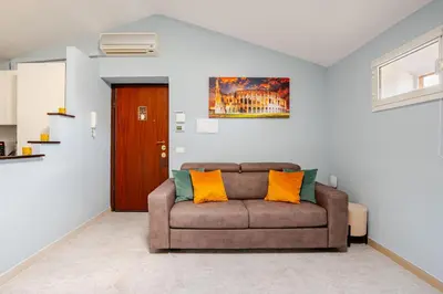 a living room with a brown couch with two orange pillows at Blue Sky Apartment - 5 min Vatican in Rome