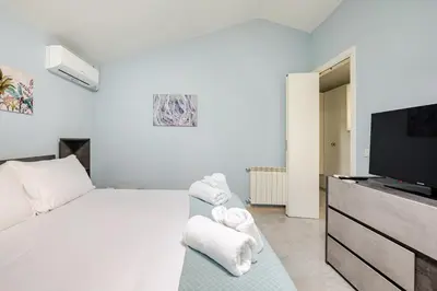 a white bedroom with a bed and a flat screen tv at Blue Sky Apartment - 5 min Vatican in Rome