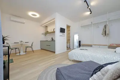 a bedroom with two beds and a kitchen with a table at Charm Apartment San Giovanni in Rome