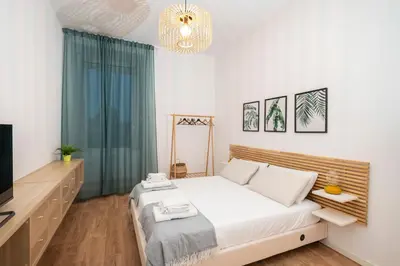 a white bedroom with a bed and a television at Casa Gazometro in Rome