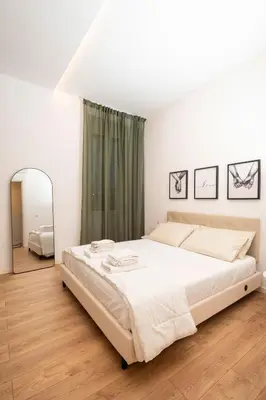 a white bedroom with a large bed and a mirror at Casa Gazometro in Rome