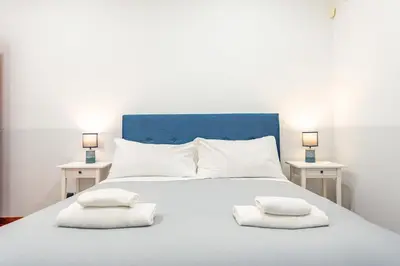 a white bed with two pillows on it with two tables at Domus 44 Apartment in Rome