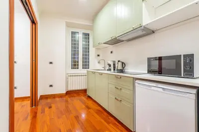 a kitchen with white appliances and a wooden floor at Domus 44 Apartment in Rome