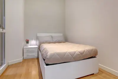 a white bedroom with a bed and a nightstand at Porta Pia Suite in Rome