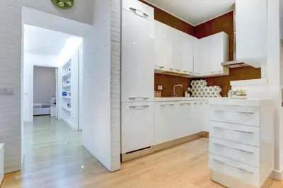 a white kitchen with white cabinets and a wooden floor at Porta Pia Suite in Rome