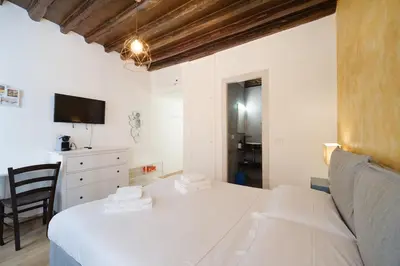 a white bedroom with a bed and a chair at Trident Suite by BuddyRent in Rome