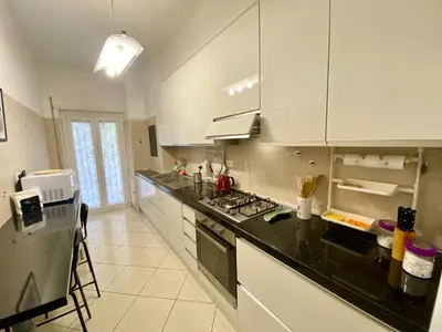 a kitchen with white cabinets and a black counter top at Mary's Apartment - House for 4 people - Close to the Vatican in Rome