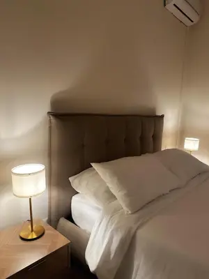 a bed with white sheets and a lamp on a table at The Apartment 56 in Rome